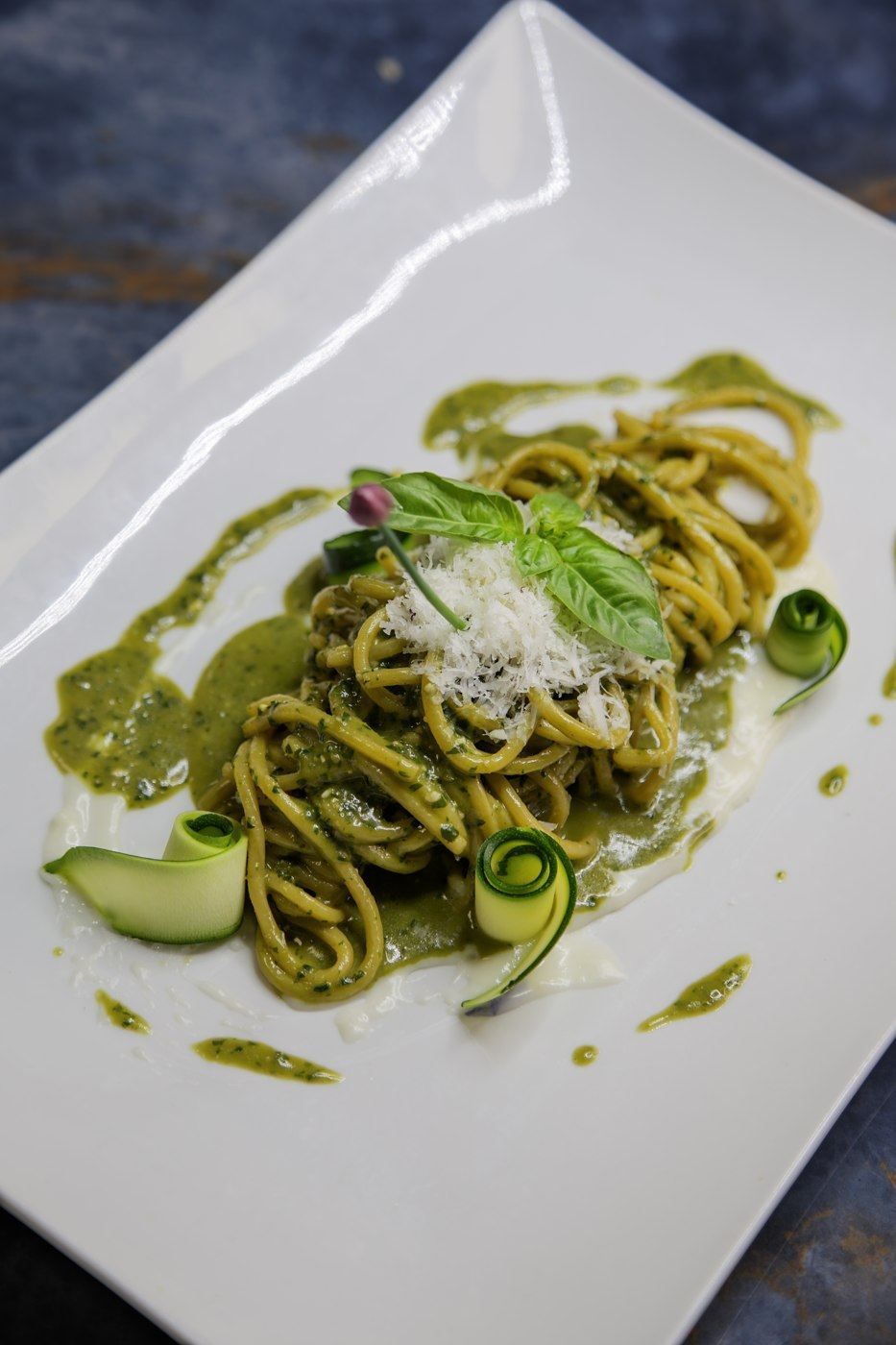 Lange Nudeln mit grünem Basilikumpesto und geriebenem Käse