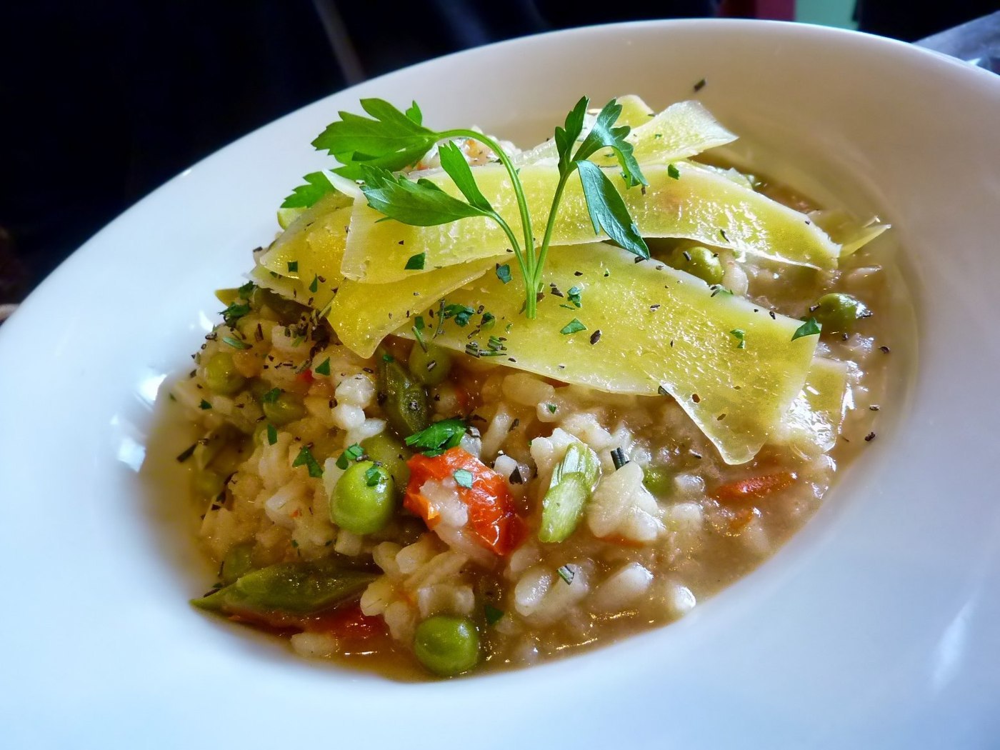 Cremiges Risotto mit Erbsen, roten Gemüsestücken und Käsehobeln