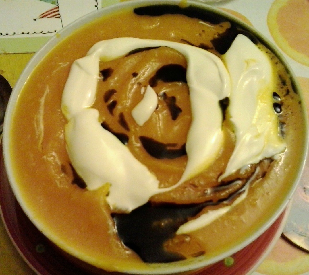Orange Kürbissuppe mit hellen Sauerrahmspuren und dunklem Kürbiskernöl