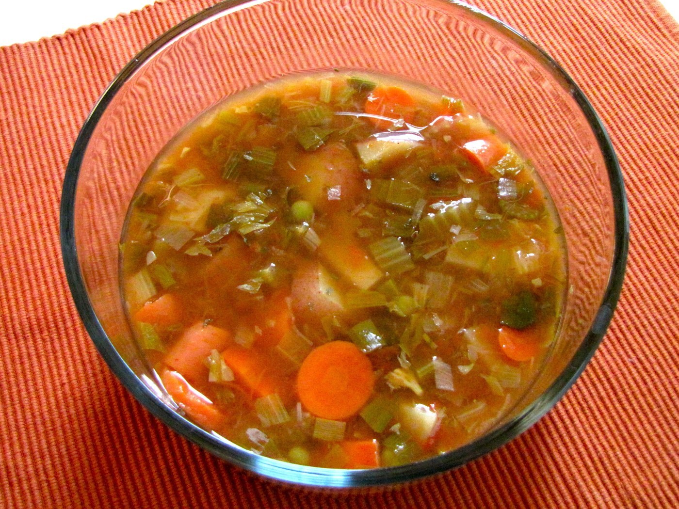 Stückige Gemüsesuppe mit Möhren, Kartoffeln, Erbsen und Bohnen in rötlicher Brühe