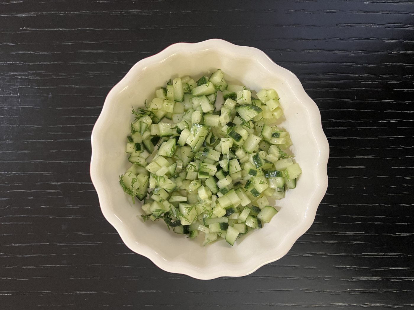 Klein gewürfelte Gurke mit Dill und heller Sauce in einer Schale