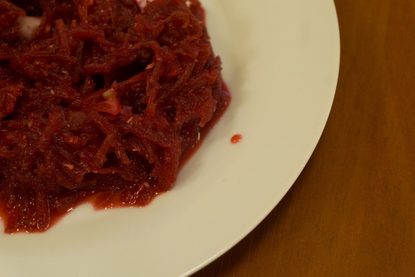 Fein geriebener dunkelroter Rote-Bete-Salat auf einem weißen Teller