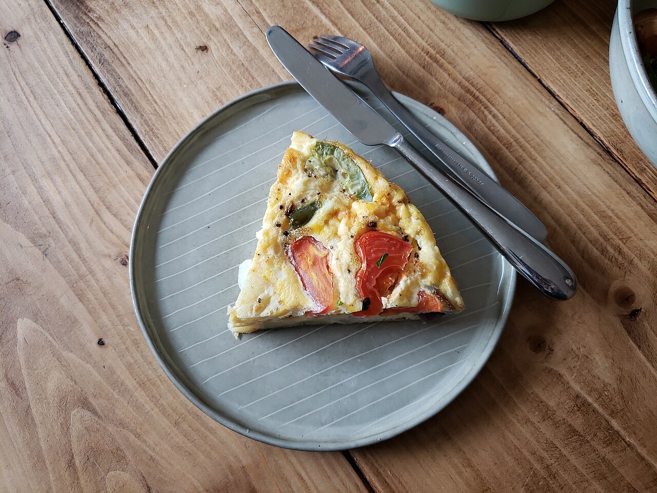 Ein Stück Frittata mit Kartoffeln, grüner Paprika und roten Tomatenstücken