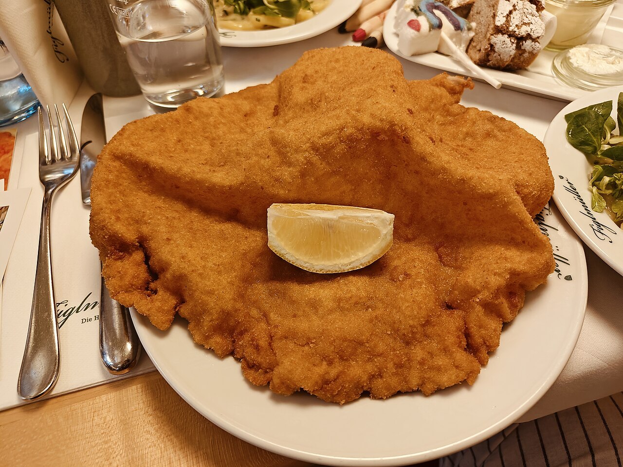 Goldbraunes paniertes Schweineschnitzel mit einer Zitronenscheibe auf einem Teller