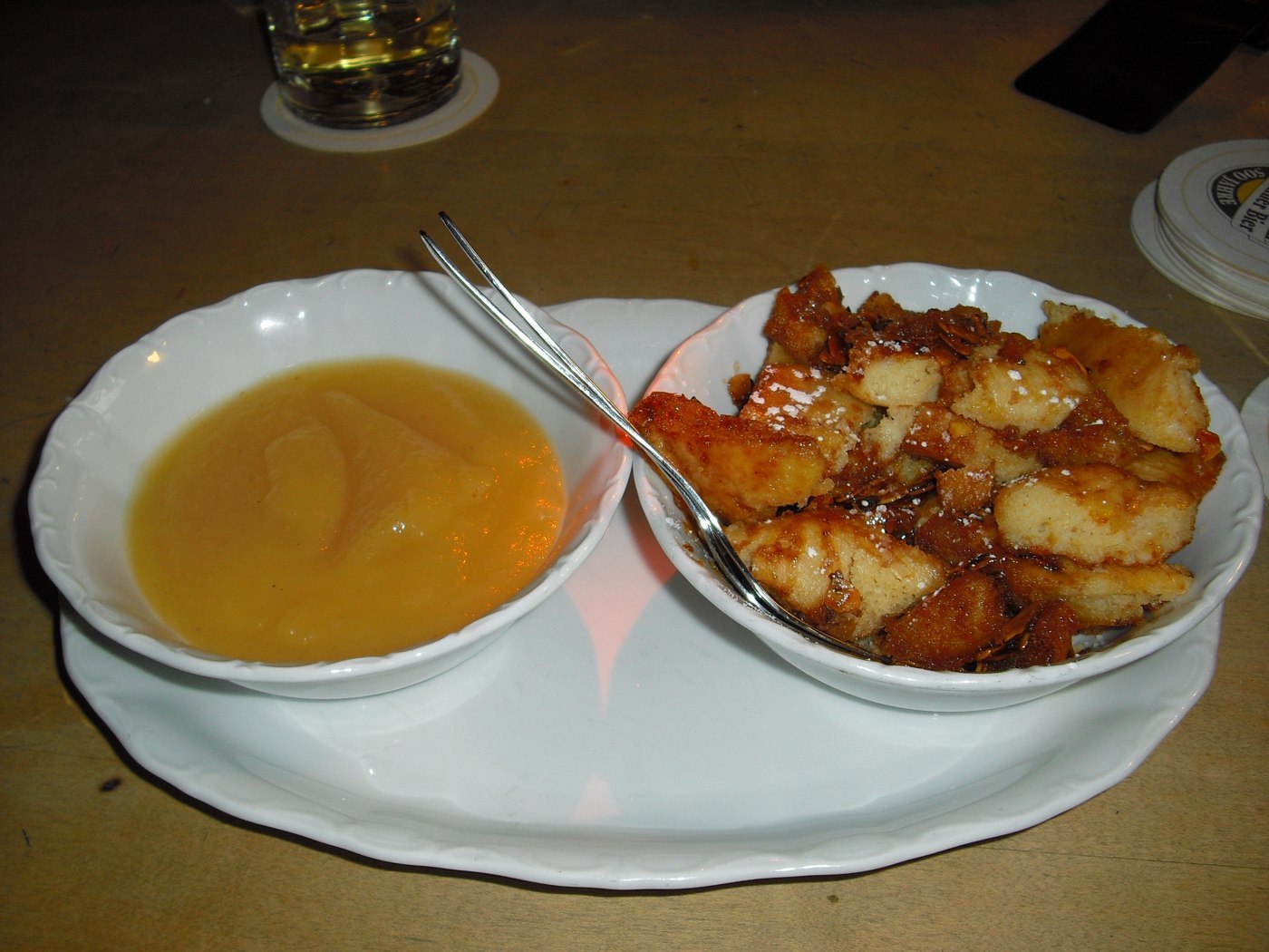 Golden torn Kaiserschmarrn in a bowl with apple sauce alongside