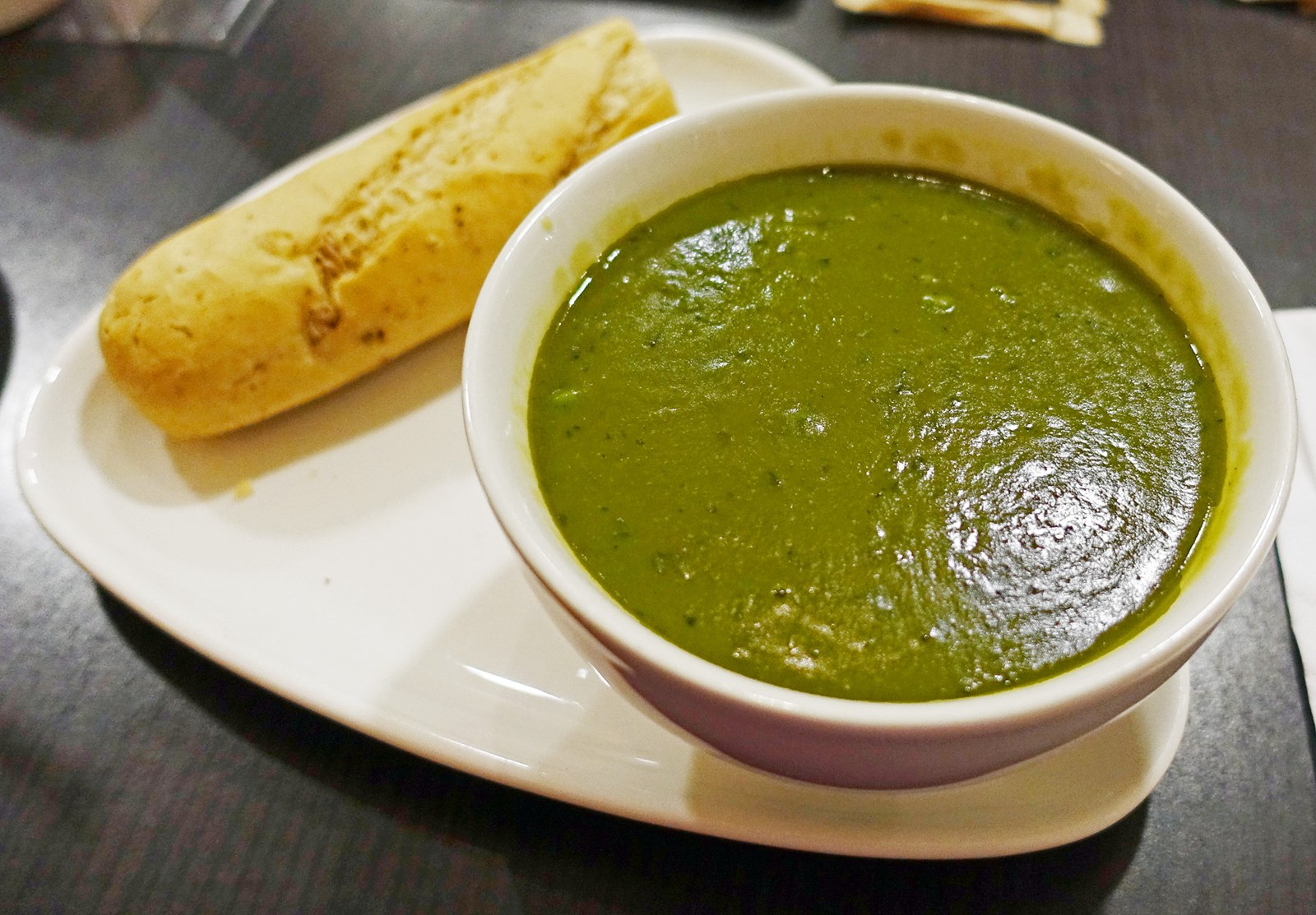 Eine Schüssel cremige grüne Erbsensuppe mit Brot
