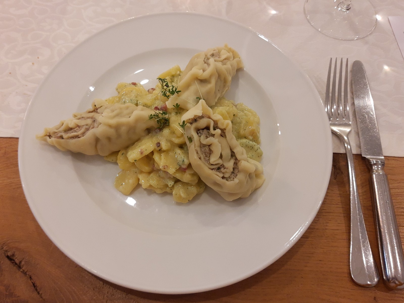 Aufgeschnittene Maultaschen auf Kartoffelsalat mit gebräunten Zwiebeln auf einem weißen Teller