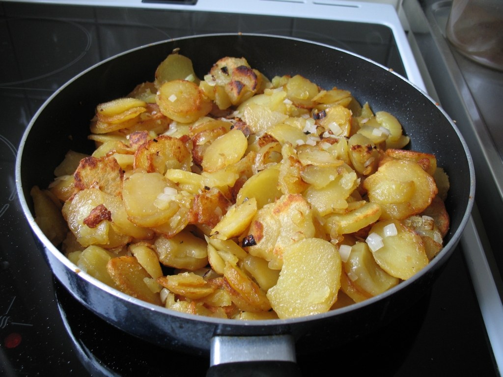 Goldbraune Bratkartoffelscheiben mit Zwiebeln in einer Pfanne