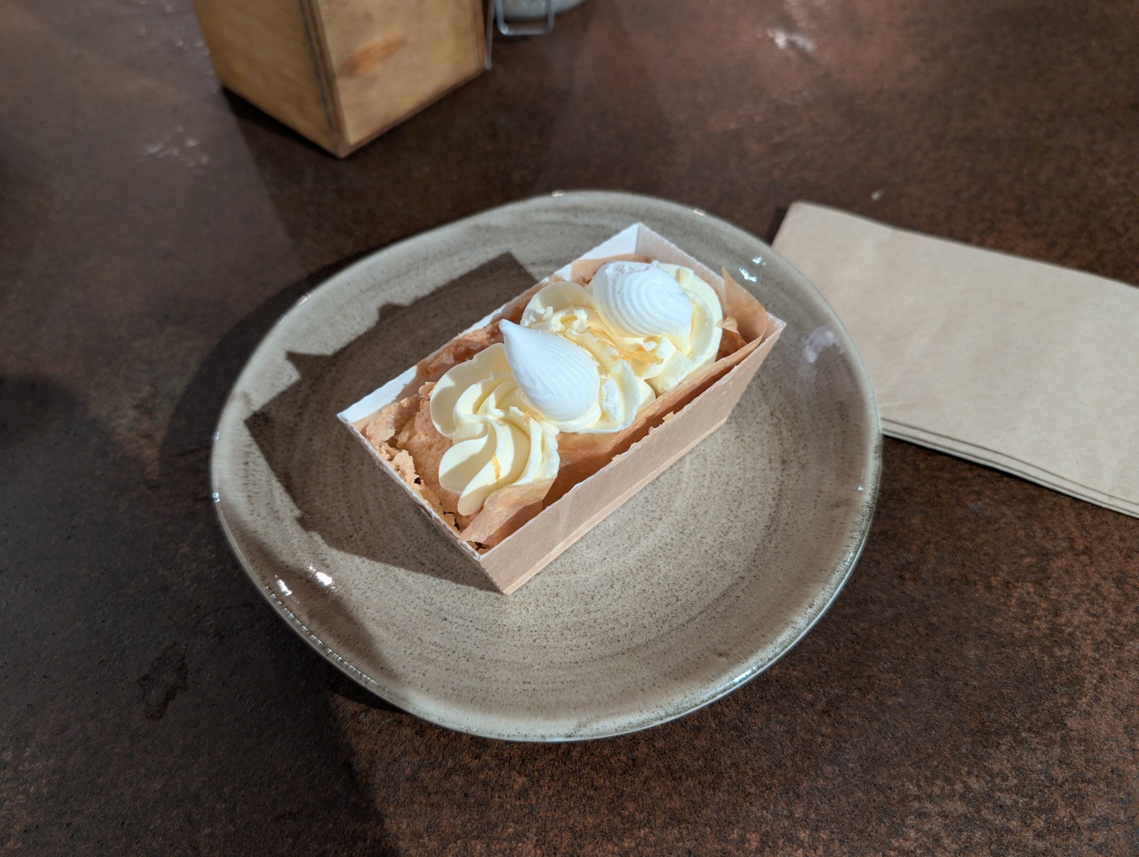 Zitronen-Holunder-Kastenkuchen mit aufgespritzter Sahne auf einem Teller
