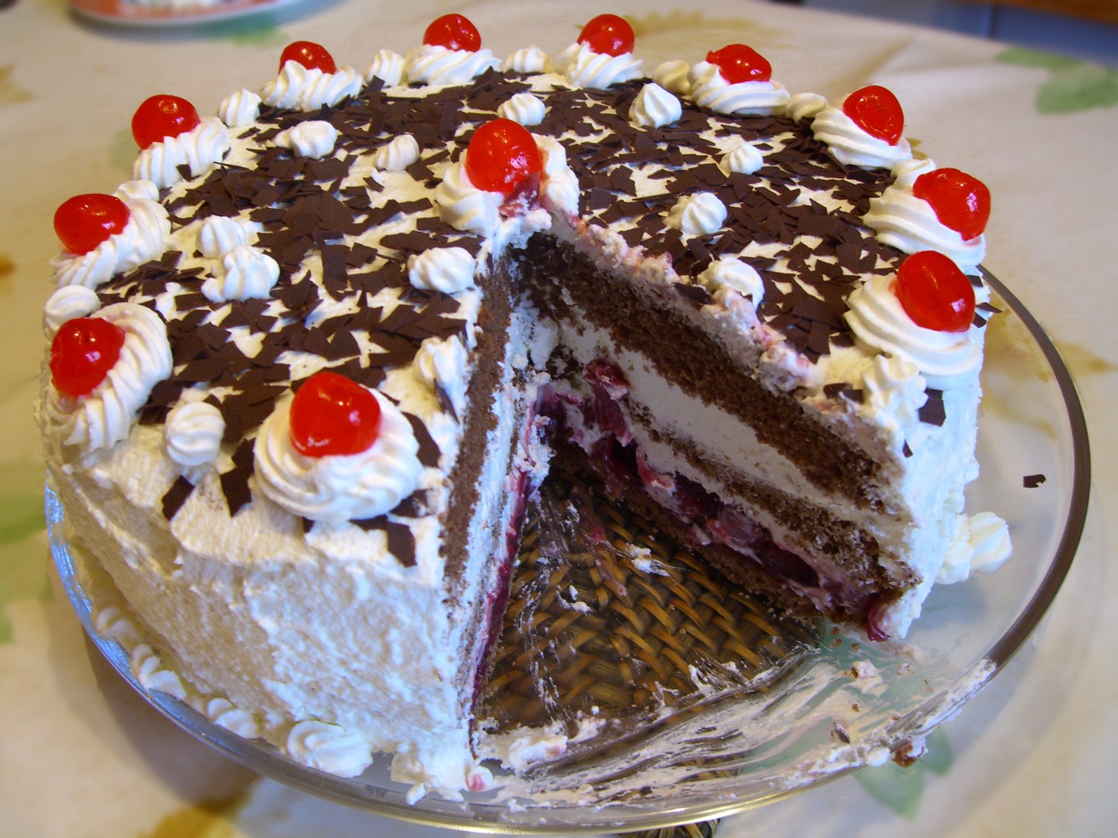 Angeschnittene Schwarzwälder Kirschtorte mit Sahne, Kirschen und Schokoladenraspeln
