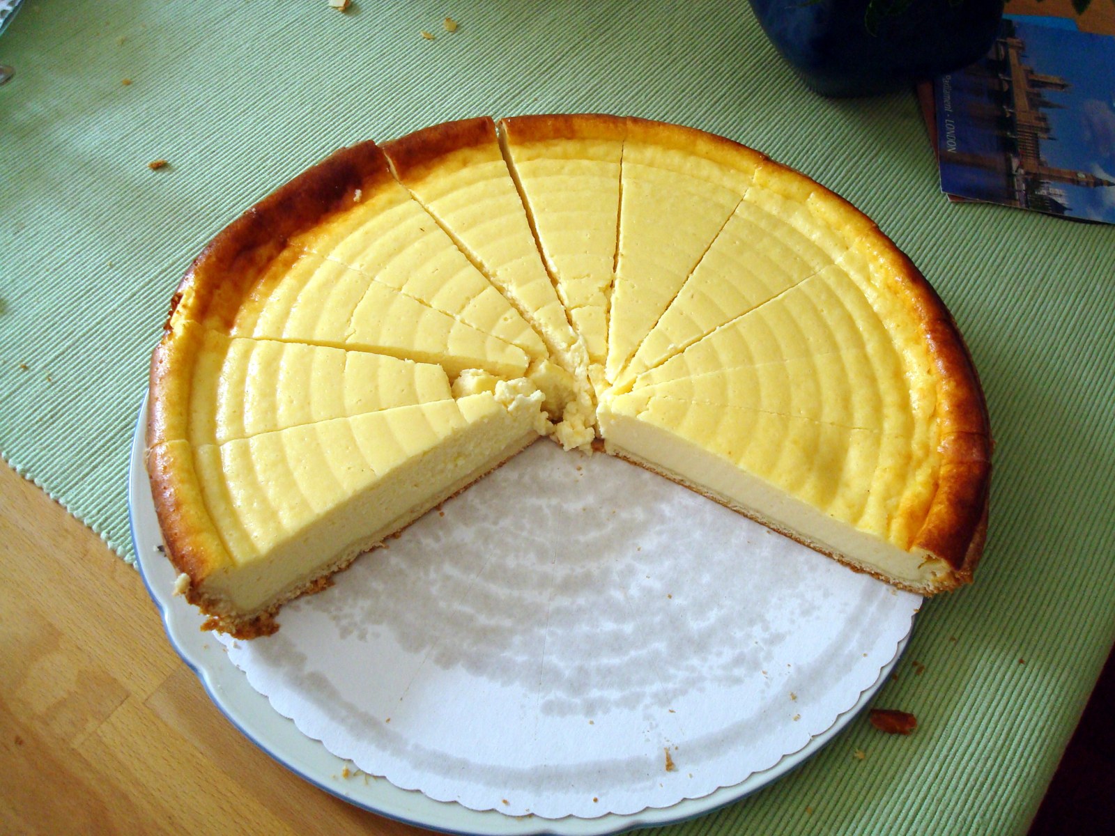 Heller runder Quark-Käsekuchen mit Mürbeteigrand und angeschnittenem Stück