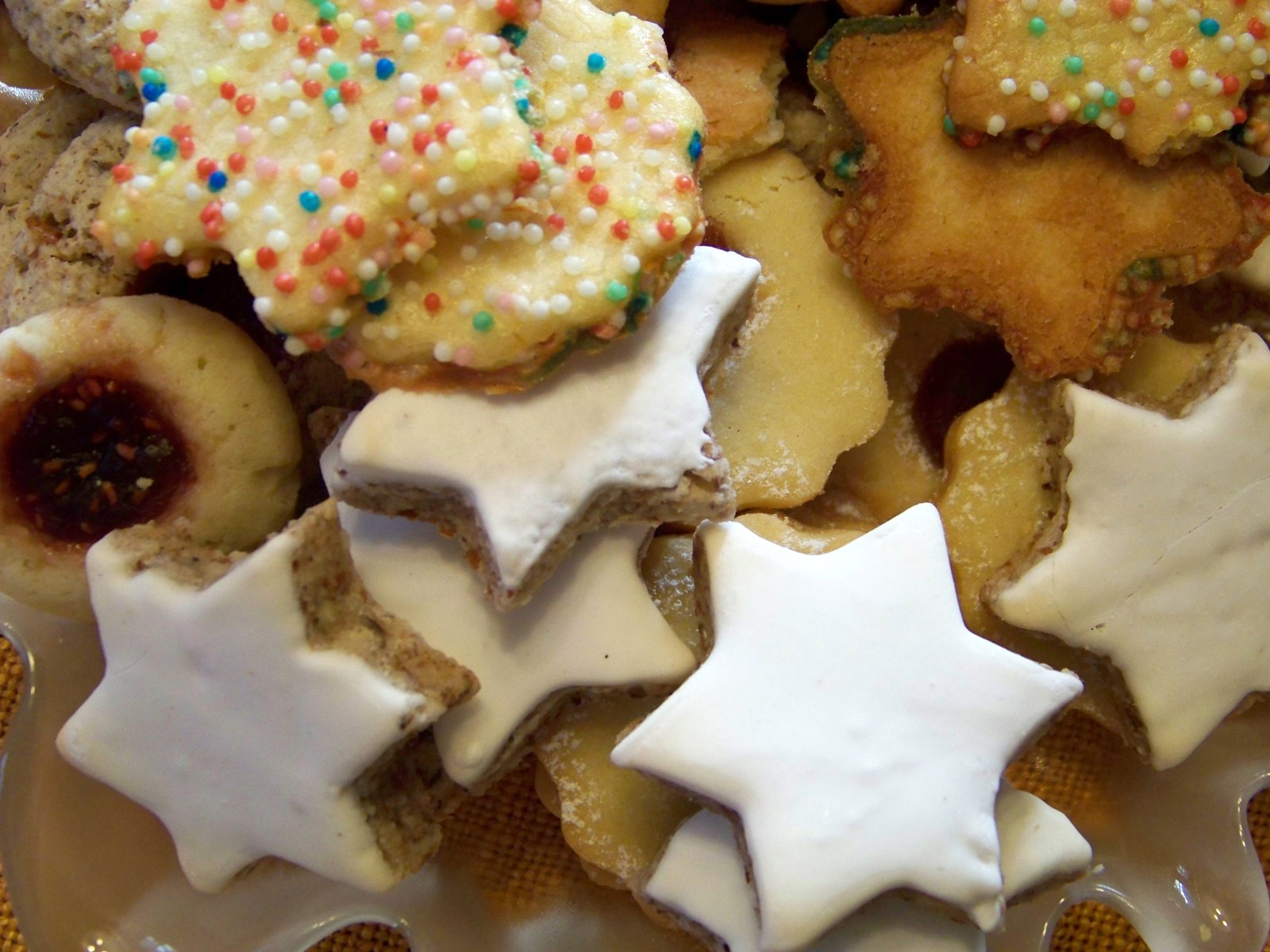 Zimtsterne mit glatter weißer Glasur zwischen weiteren Weihnachtsplätzchen