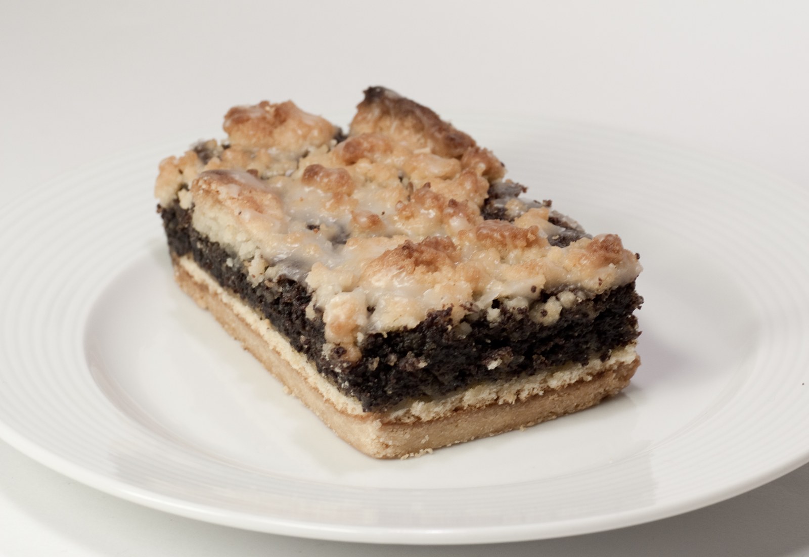 Mohnkuchenstücke mit dunkler Füllung zwischen hellem Boden und goldenen Streuseln