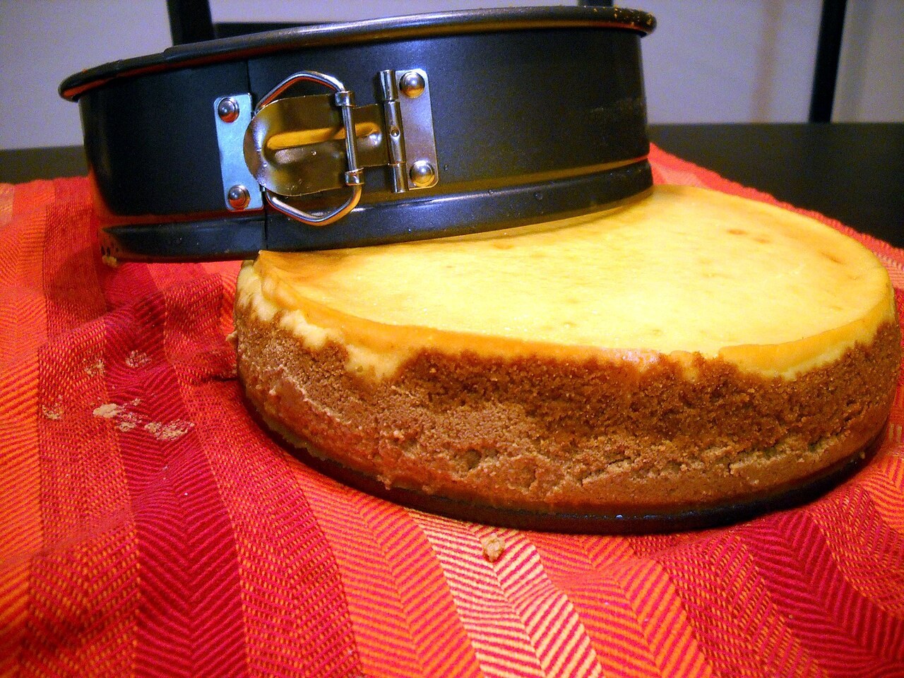 An open springform tin beside a baked round cake