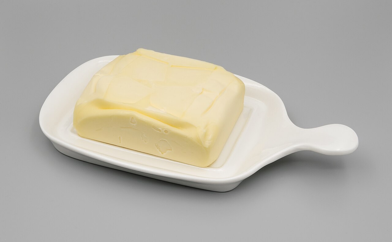 Ein Stück Butter in einer weißen Butterdose
